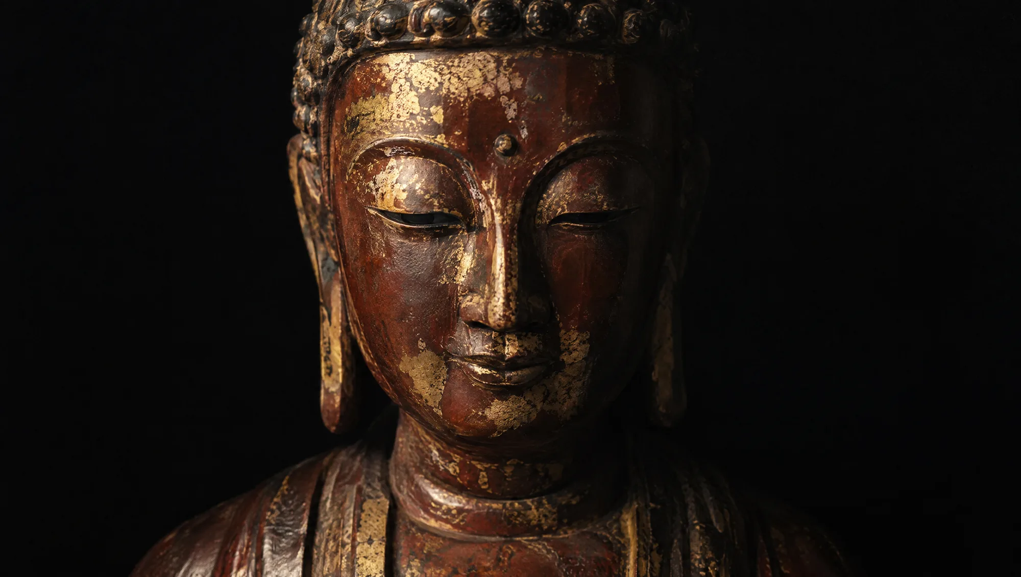 A Vietnamese Buddha in red-brown lacquered wood with worn gold leaf