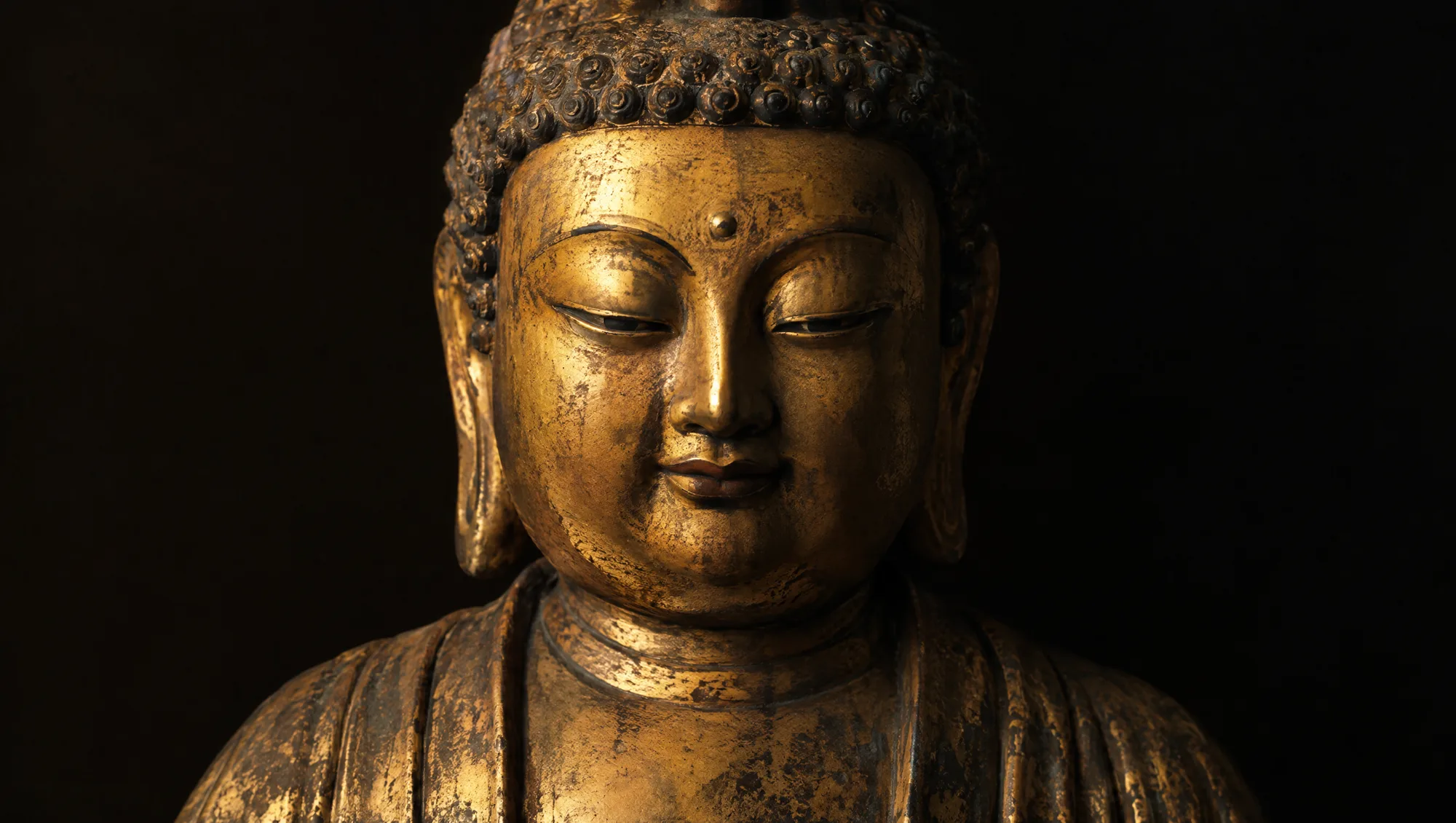 A Tang dynasty gilded bronze Buddha with a round full face and small smile
