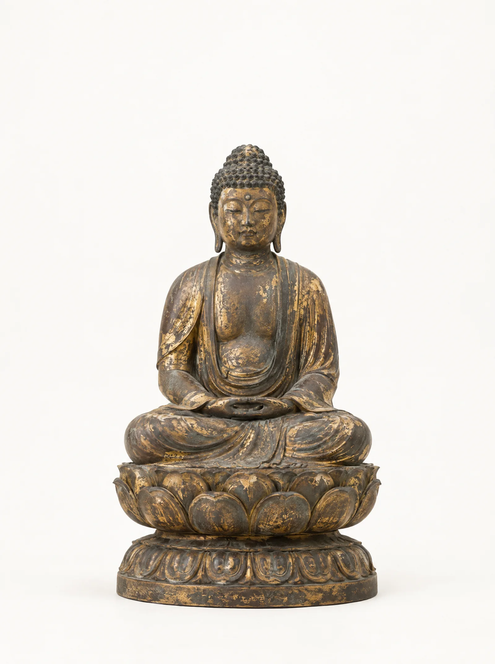 A seated Shakyamuni Buddha in aged bronze with worn gold leaf, photographed on a bone-white background