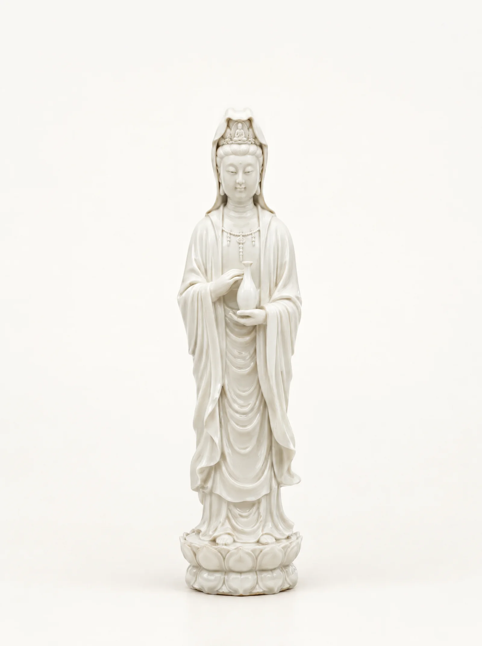 A standing Guan Yin in white Dehua porcelain holding a small vase, on a bone-white background