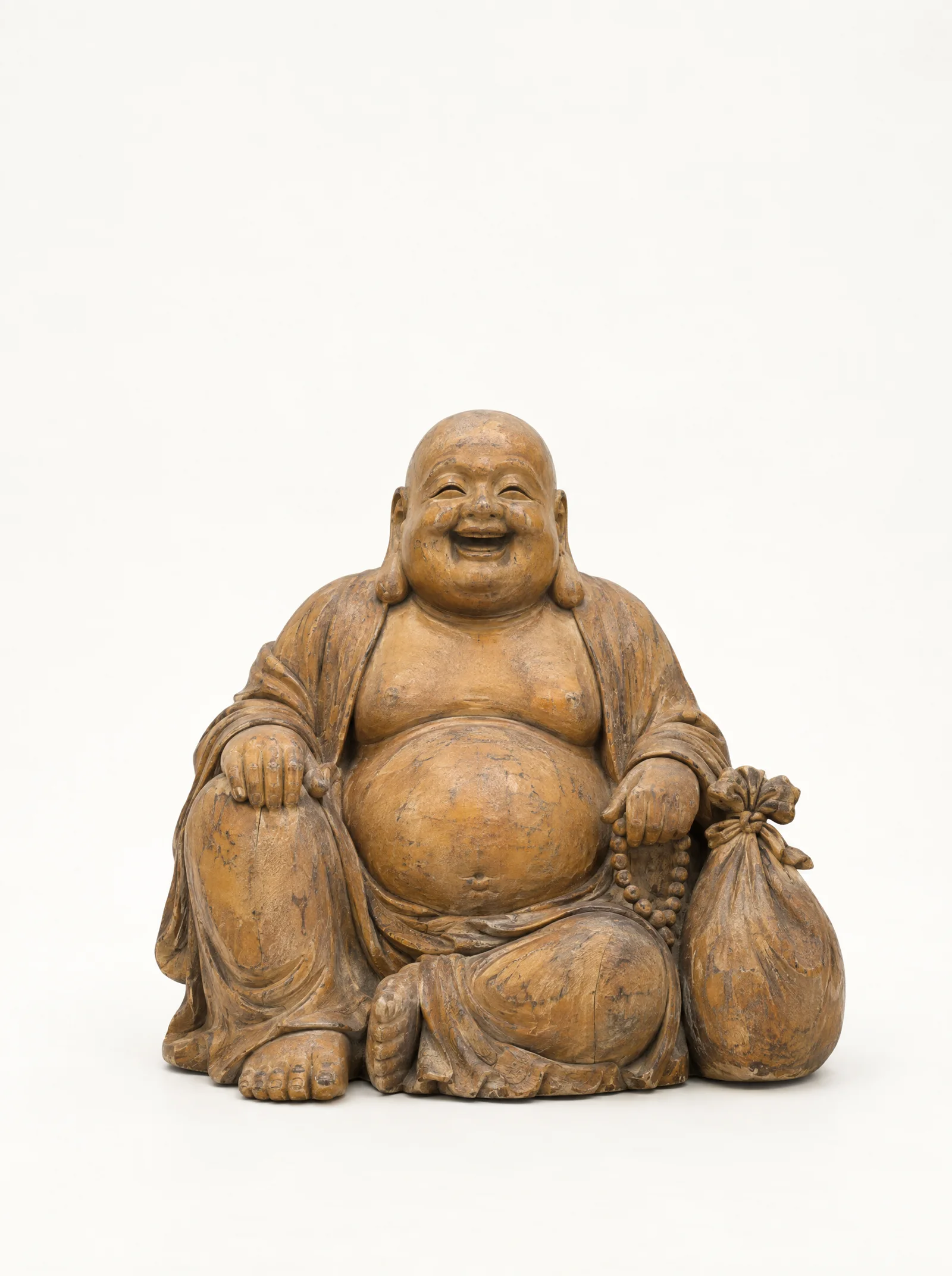 A laughing Maitreya carved in worn honey-coloured wood with a cloth sack